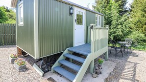 A small, single-story shed with a door and a small porch with steps leading up to it.