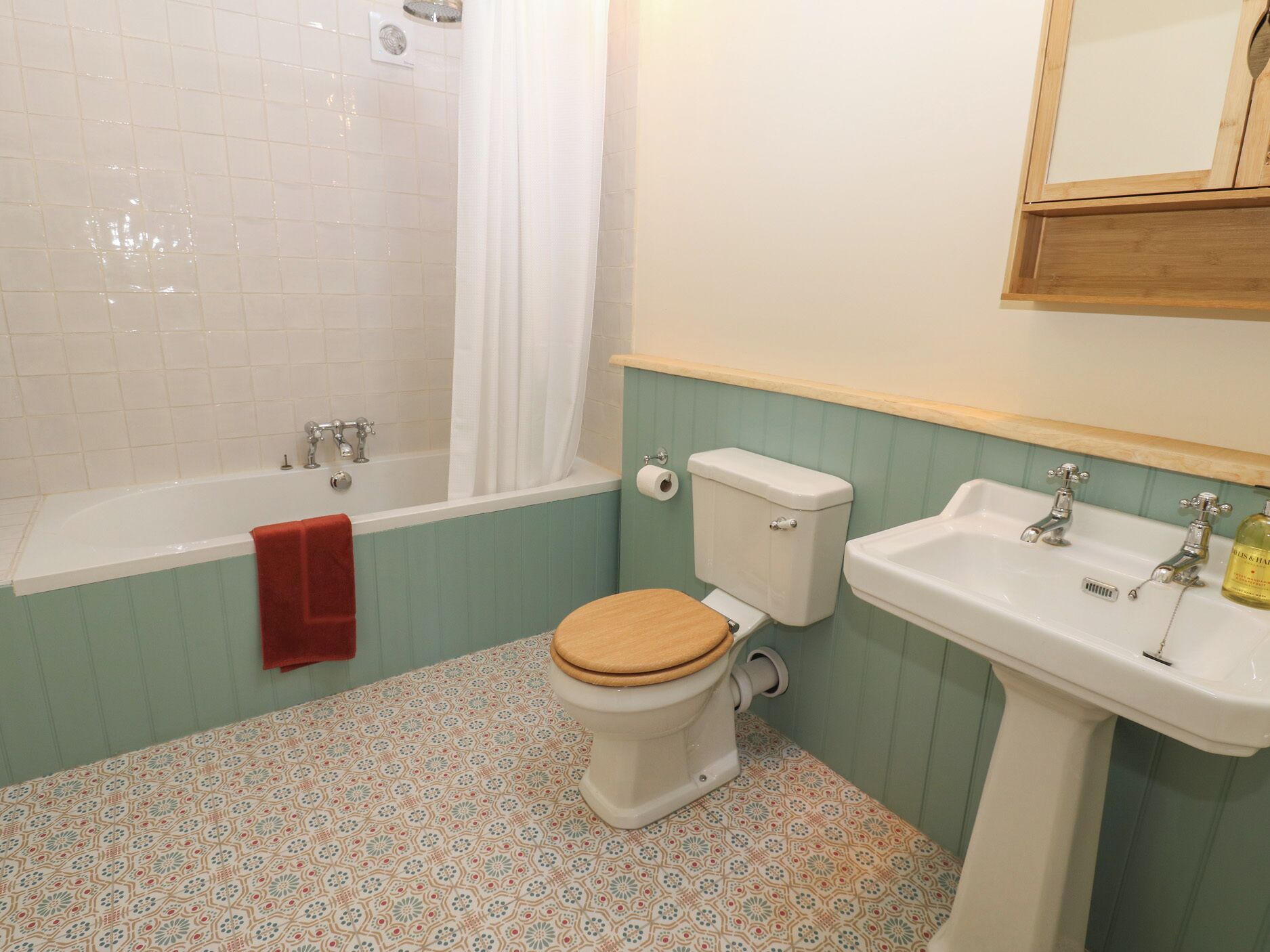 A bathroom with a bathtub, toilet, sink, and patterned floor tiles.