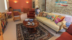 Una sala de estar acogedora con un sofá, sillones, una mesa de centro y una estantería.