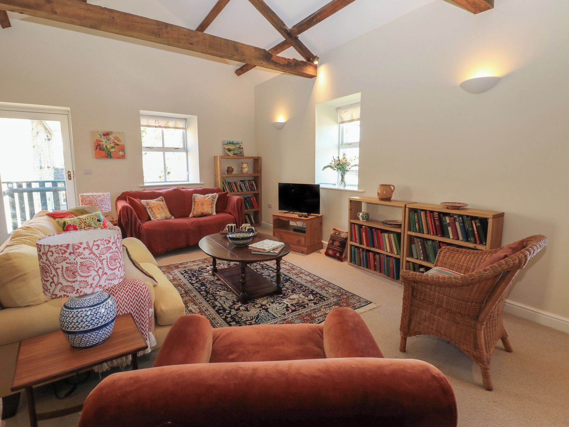 A cozy living room with a sofa, armchair, and a television. There are bookshelves and a coffee table.