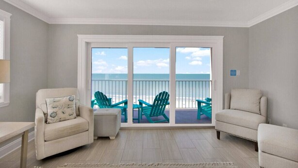 Ein Zimmer mit Blick auf den Strand, zwei Stühle, ein kleiner Tisch und ein Fenster zum Meer.
