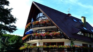 Una tradicional cabaña con varios balcones decorados con flores, tejado inclinado y chimenea.