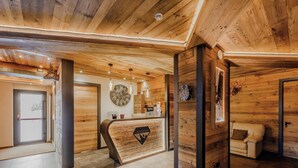 A wooden interior with a reception desk, a clock, and a sofa. - Hotiday Sauze Centro (Sauze d'Oulx)