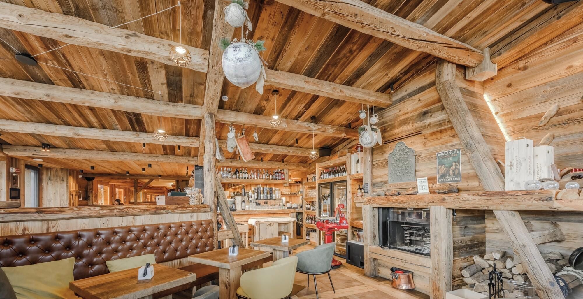 Un interior rústico de madera con barra, asientos y chimenea.