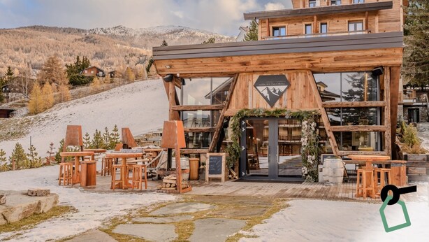 Un chalet de madera con una pista de esquí al fondo.