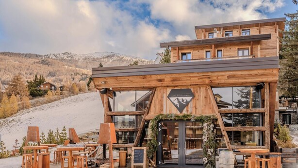 Un chalet de madera con una pista de esquí al fondo.