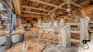 Interior rústico de madera con una zona de bar, asientos y vistas al exterior.