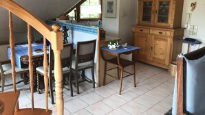 A kitchen with a dining area, wooden cabinets, and a staircase. - Apartment 'Schwalbennest' with Mountain View, Private Balcony and Wi-Fi (Sasbachwalden)