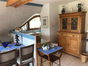 A kitchen with a dining area, wooden cabinets, a blue tablecloth, and a chandelier.