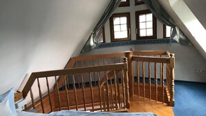 A bedroom with a wooden staircase, a bed with a blue sheet, and a blue carpet. - Apartment 'Schwalbennest' with Mountain View, Private Balcony and Wi-Fi (Sasbachwalden)