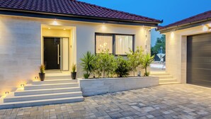 A modern house with a tiled roof, a front entrance with steps, and a landscaped garden. - Villa Ballat (Privlaka)