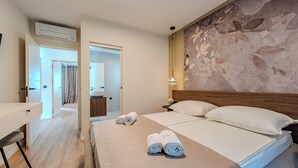 A hotel room with a bed, a desk, and a bathroom visible through an open door. - Villa Ballat (Privlaka)