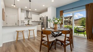 Una cocina moderna con armarios blancos, electrodomésticos de acero inoxidable y taburetes de madera.