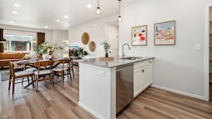 Una cocina moderna con una isla central, armarios blancos e iluminación colgante.
