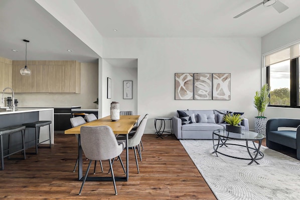 A modern living space with a dining area, kitchen, and seating area.