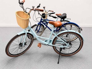 A light blue bicycle with a wicker basket, brown leather seat, and a rear rack.