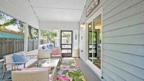 A covered porch with wicker furniture and a tropical rug. - 3BR Coastal Home Near Beach w/ Fire Pit (St. Augustine)