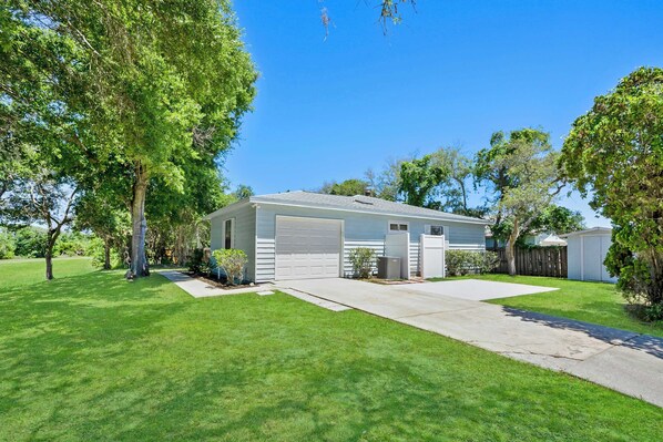 A single-story house with a garage, a front yard, and a small shed.