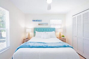 A bedroom with a bed, two bedside tables, a window, and a wardrobe.
