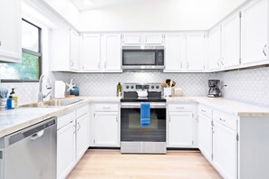 A modern kitchen with white cabinets, a stainless steel oven, and a microwave.