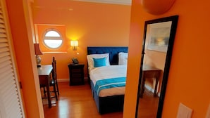 Een hotelkamer met een bed, een bureau, een stoel, een lamp en een raam.