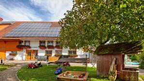 Ein Haus mit Solaranlage, Garten, Spielbereich und einer Holzkonstruktion.