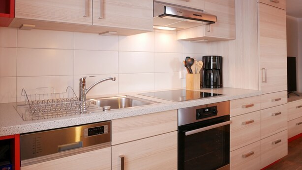 Eine moderne Küche mit Geschirrspüler, Backofen und einer Kaffeemaschine auf der Arbeitsfläche.