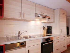 Een moderne keuken met een vaatwasser, oven en koffiezetapparaat op het aanrecht.