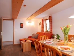 A dining area with a wooden table, chairs, and a vase with flowers.