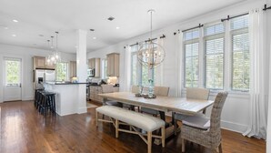 A spacious kitchen with wooden flooring, a central island, and bar stools.
