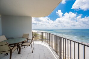 Un balcon avec vue sur l’océan, une table ronde avec des chaises et une rambarde.