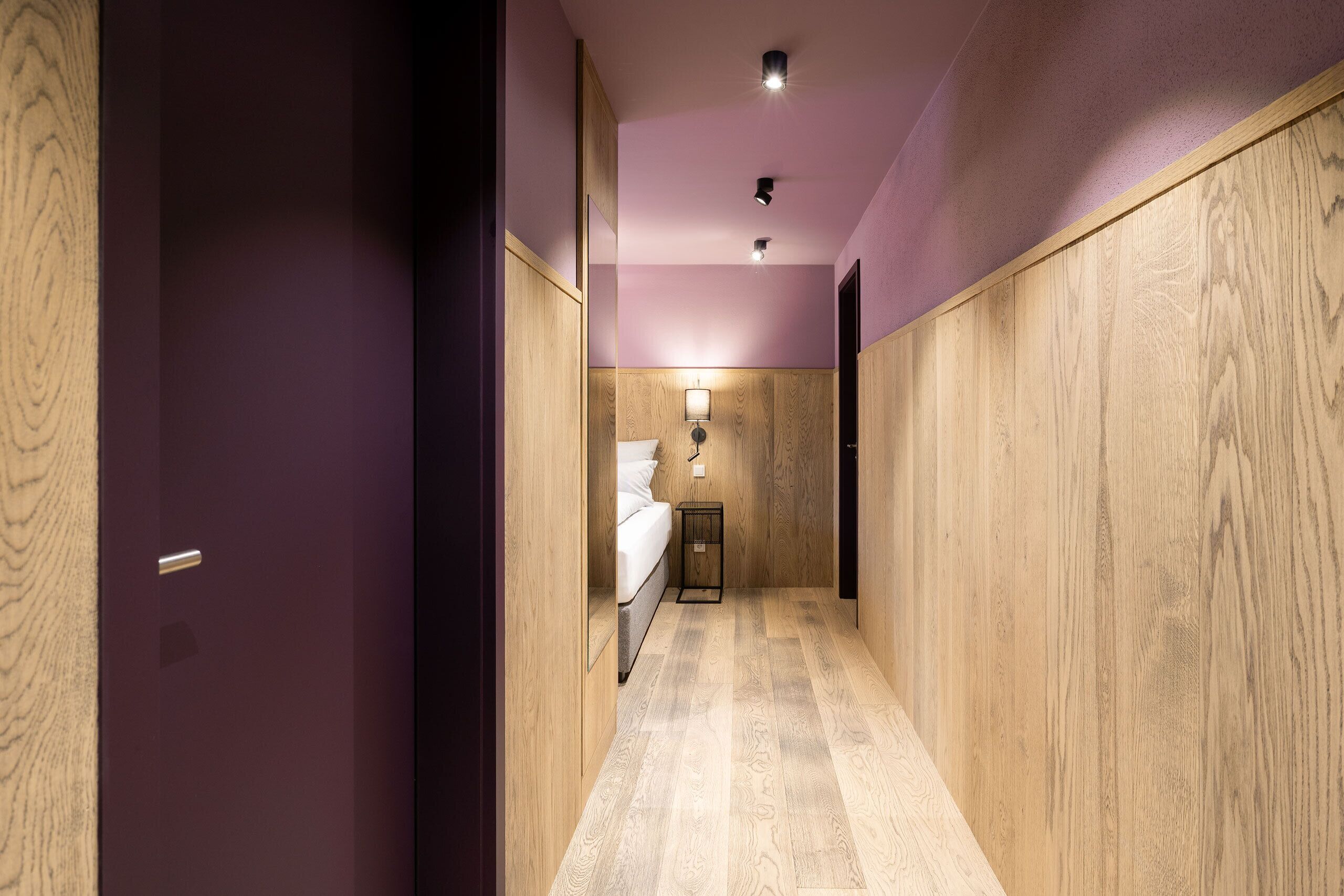 A narrow hallway with wooden paneling on the walls and a light-colored floor.