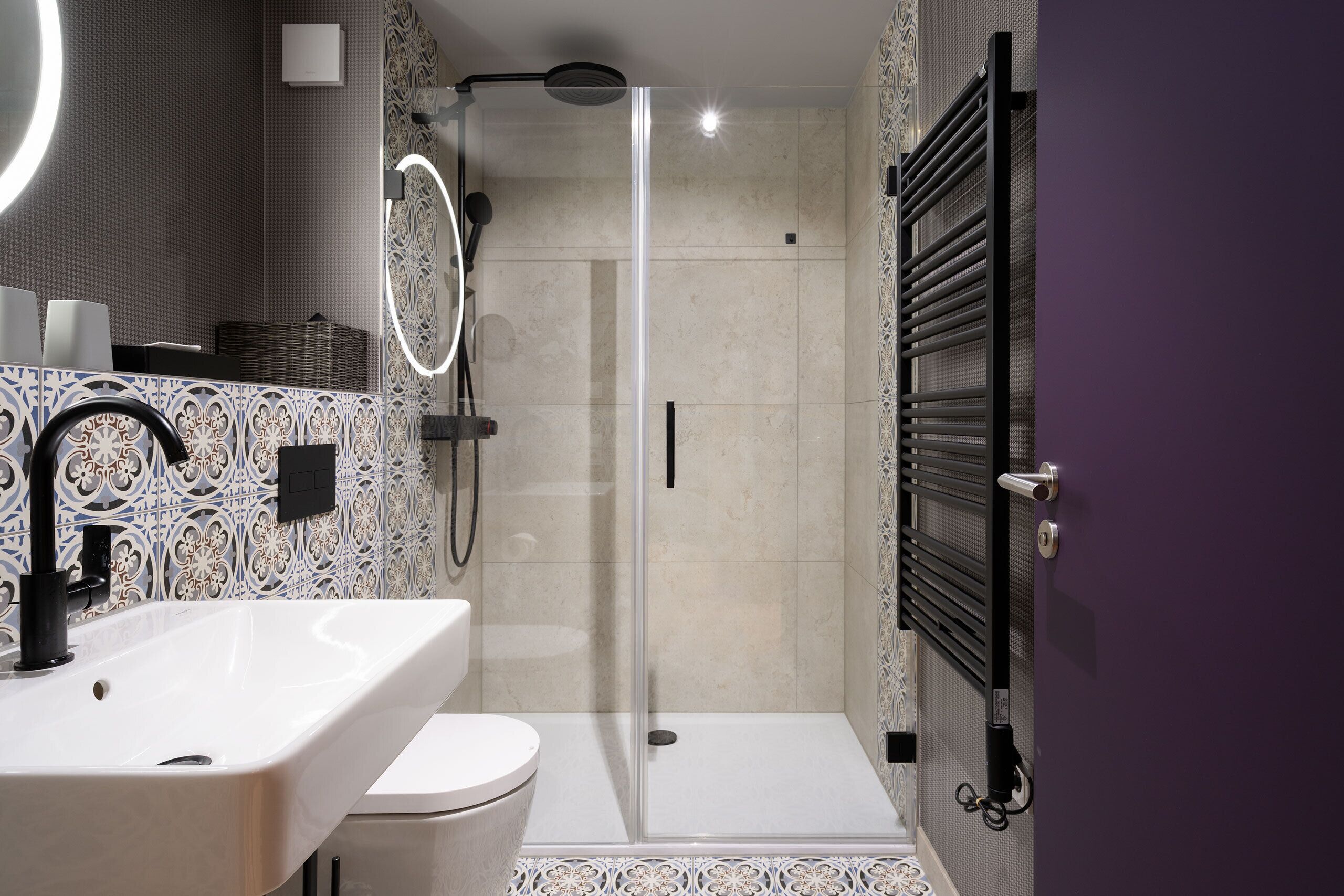 A modern bathroom with a glass-enclosed shower, a white sink, and a toilet.