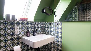 A bathroom with a white sink, green walls, and patterned tiles.