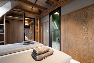 Ein Schlafzimmer mit einem großen Bett, einem Holzschrank und Blick auf eine grüne Außenanlage.
