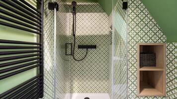 A shower with a geometric patterned wall, a wooden shelf, and a black faucet.