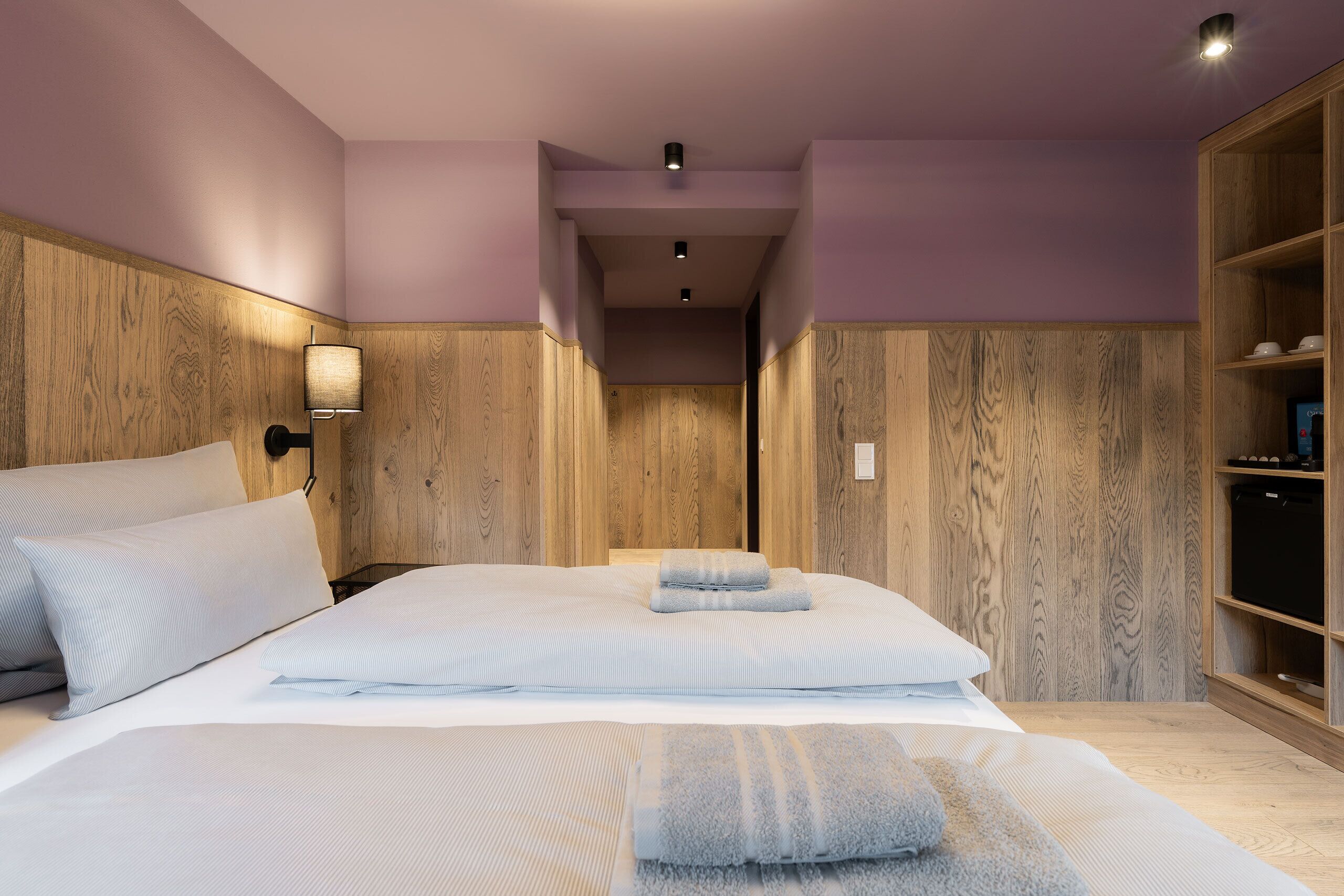 Ein Hotelzimmer mit einem großen Bett, Holzwandverkleidung, einem Nachttisch mit Lampe und einem Kleiderschrank.