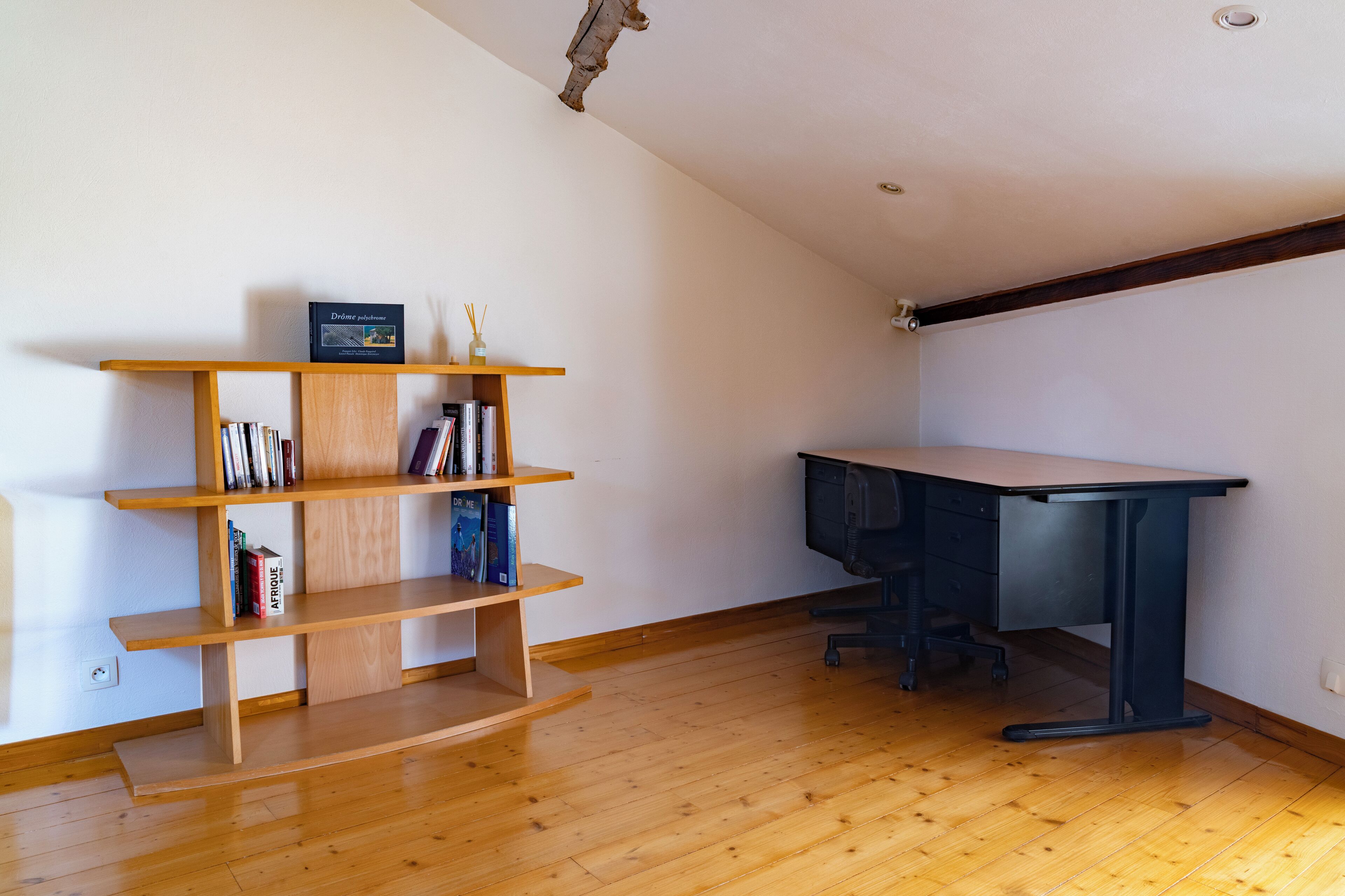 Una habitación con una estantería de madera, un escritorio y una silla.