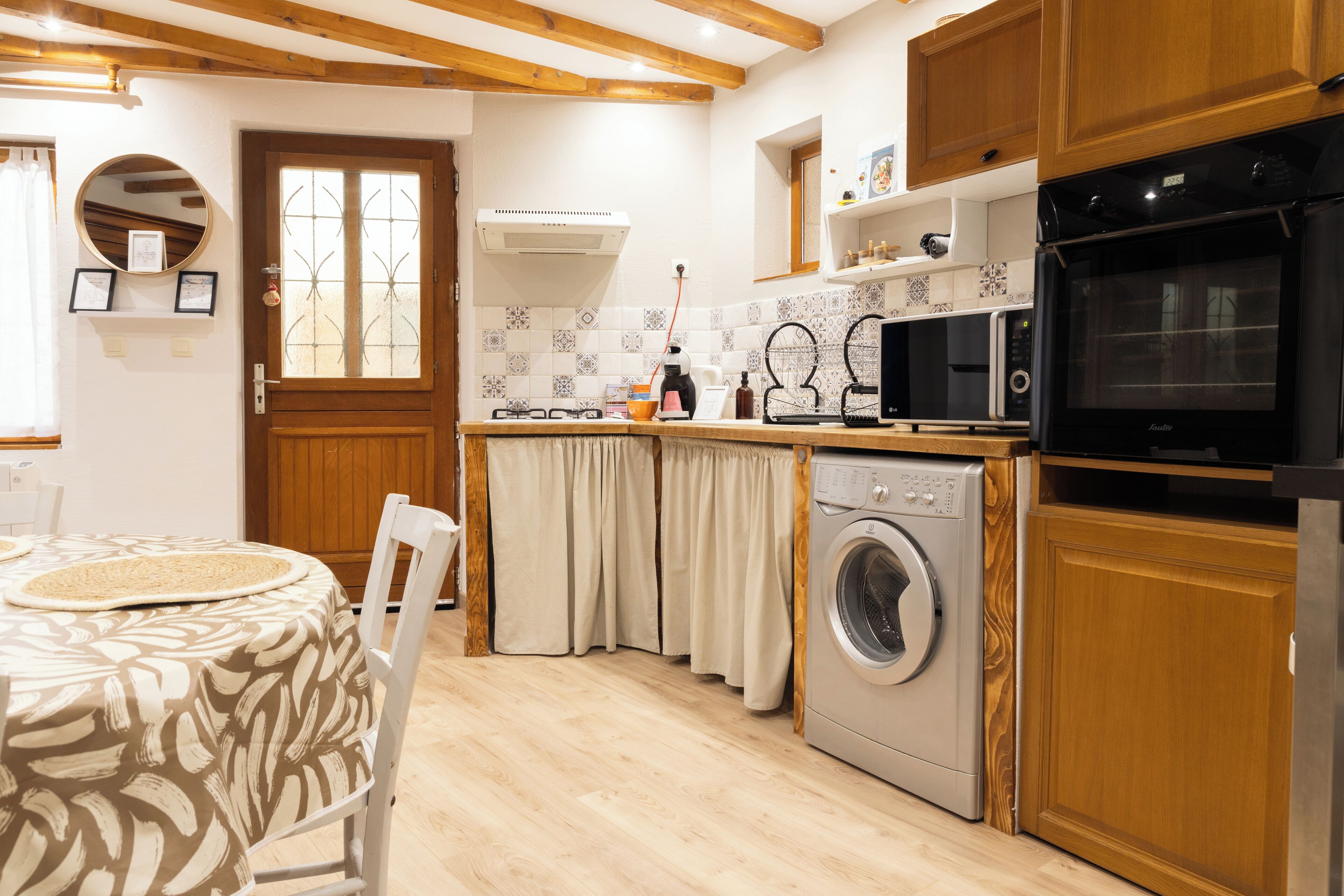 Una cocina con armarios de madera, lavadora, microondas y comedor con mesa y sillas.