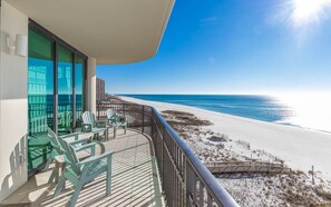 A balcony with chairs and a table overlooking a beach. - Phoenix Ix 508 3 Bedroom Condo (Orange Beach)