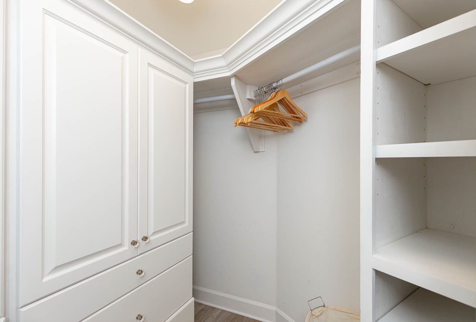 Un angle d'una habitació amb parets blanques, una porta blanca i un moble prestatge blanc.