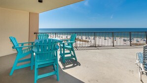 En balkon med turkise Adirondack-stole og udsigt til stranden.