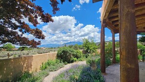 Un espacio al aire libre cubierto con vistas a un jardín ajardinado y montañas lejanas.