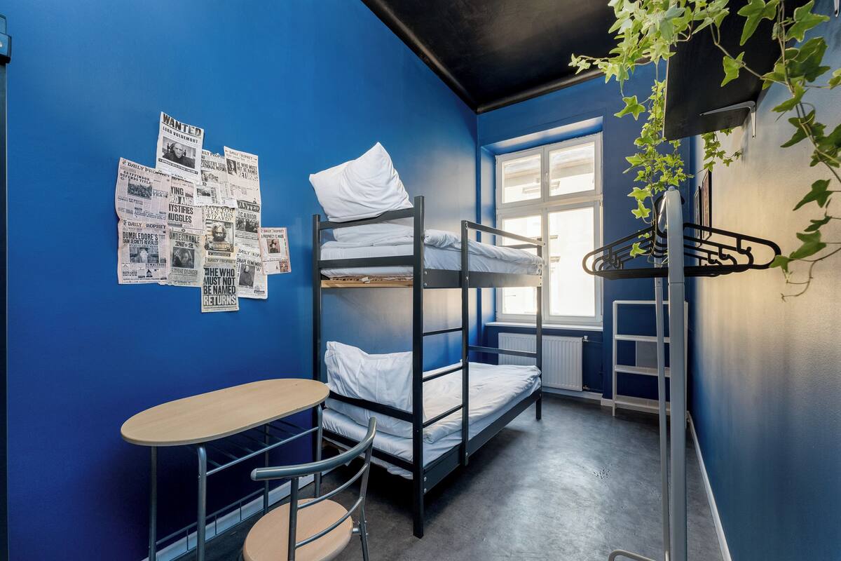 A dormitory room with bunk beds, a small table, and chairs.