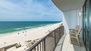 Un balcon donnant sur une plage, une chaise et une rambarde.