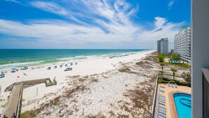 A beach view with a pool, beach umbrellas, and a boardwalk leading to the beach. - Phoenix Ix 505 3 Bedroom Condo (Orange Beach)