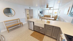 A modern kitchen with a built-in dishwasher, a large island with a sink, and a wooden bench.