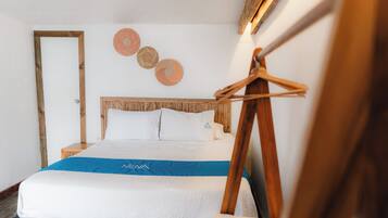 Una cama bien hecha con una colcha azul y blanca, un cabecero de madera y tres adornos circulares en la pared.