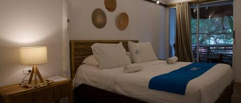 A neatly made bed with a blue blanket, a bedside lamp, and a wooden nightstand.