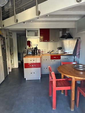 Une cuisine moderne avec un coin repas, des appareils en acier inoxydable et une décoration aux couleurs rouge et blanche.
